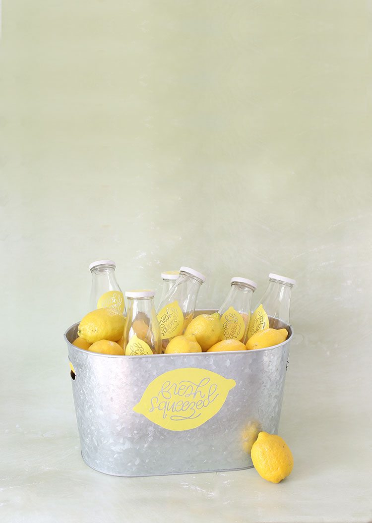 Galvanized Steel Tub of Drinking Bottles and Lemons on Green Background