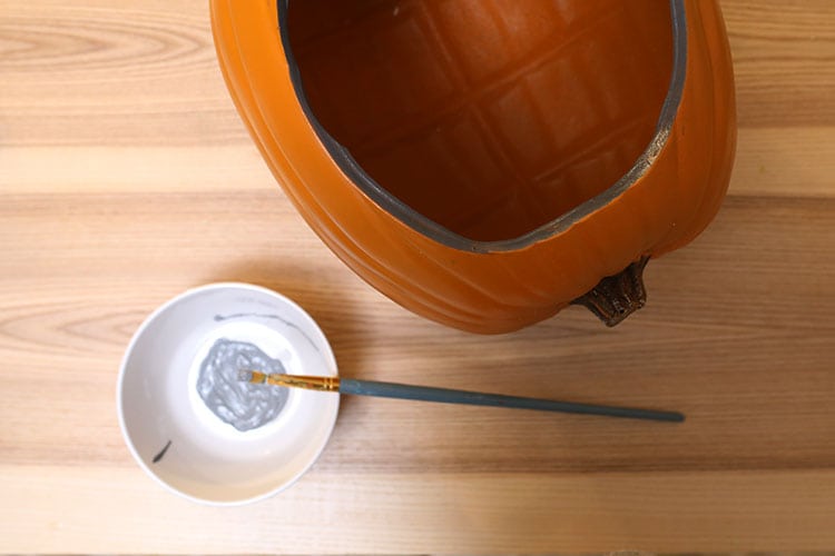 Painting the rim of a fake foam diorama pumpkin for Halloween