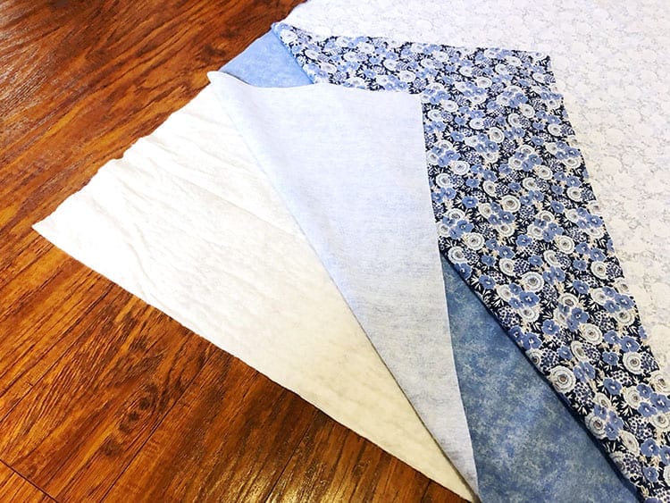 Three sheets of fabric layered on top of each other on a wood floor