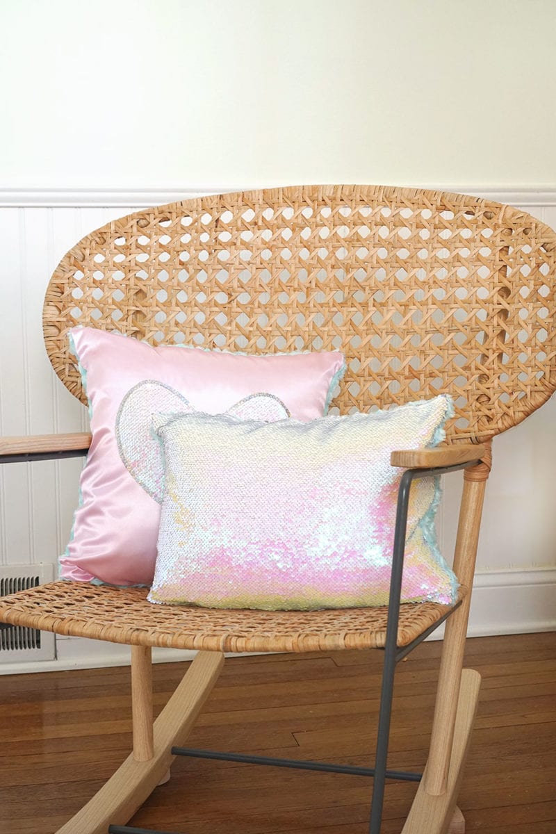 Pink heart magic sequin pillow and iridescent mermaid sequin pillow on wicker rocking chair