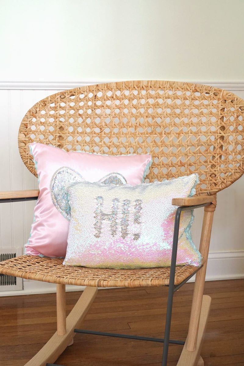 Pink heart magic sequin pillow and iridescent mermaid sequin pillow on wicker rocking chair