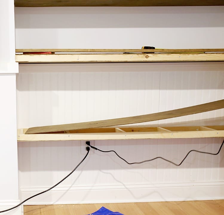 Floating shelves being built and installed against a very light blue wall