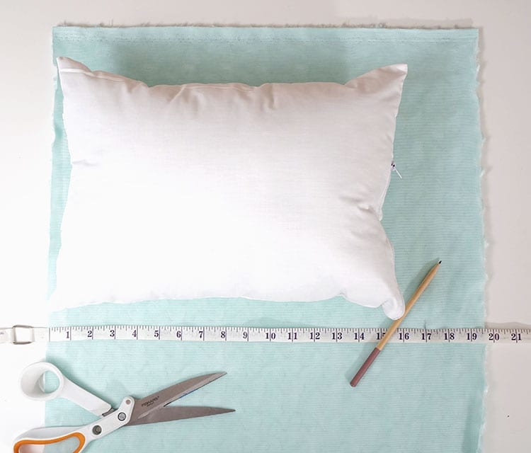 Sewing tape measure and pencil on turquoise fabric for making a magic sequin pillow