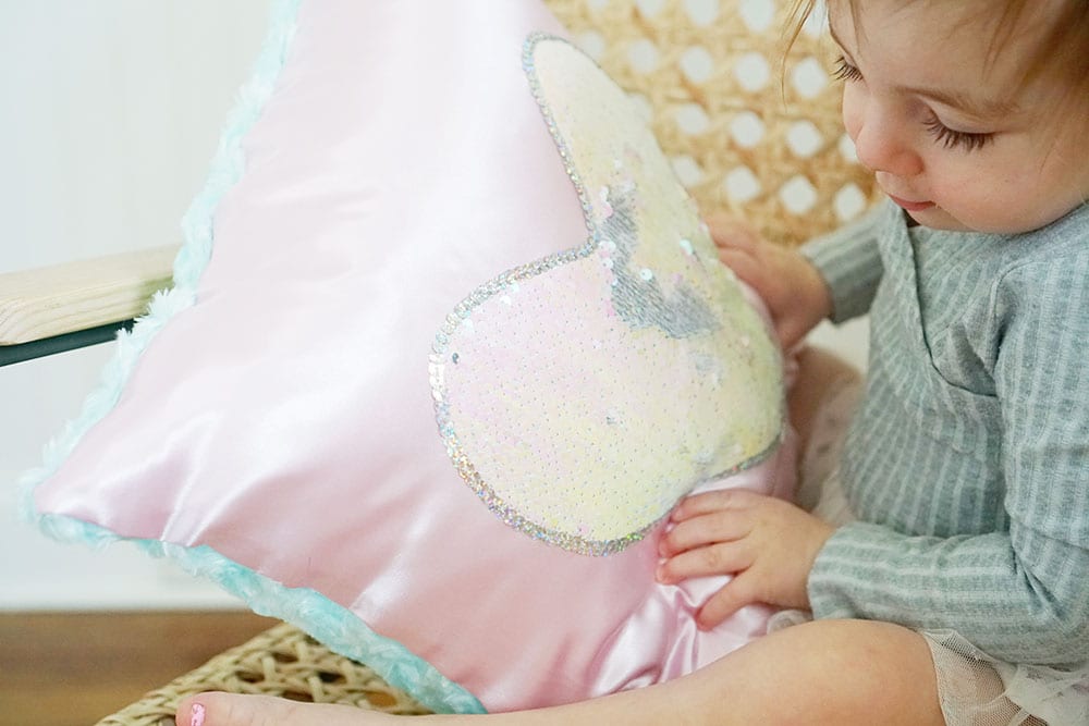Toddler hands playing with a pink heart shaped magic sequin pillow