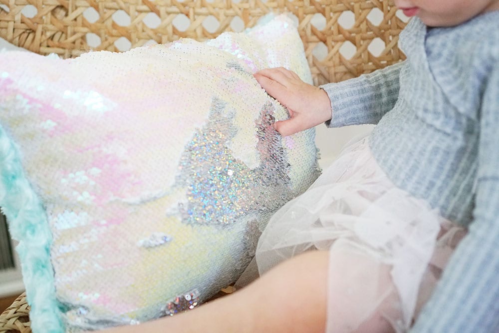 Toddler hands playing with a pink heart shaped mermaid sequin pillow