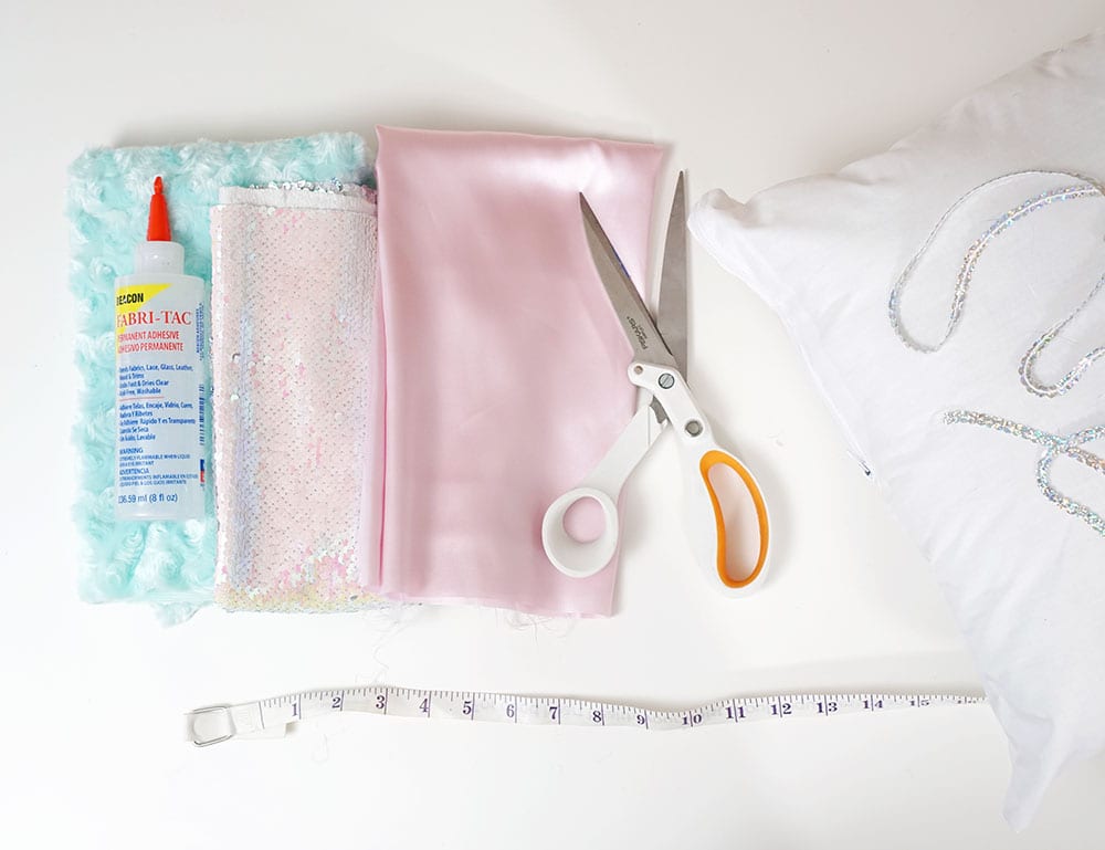 Fabric, sewing scissors, Beacon Adhesives Fabri-Tac glue, and pillow insert for magic sequin pillow