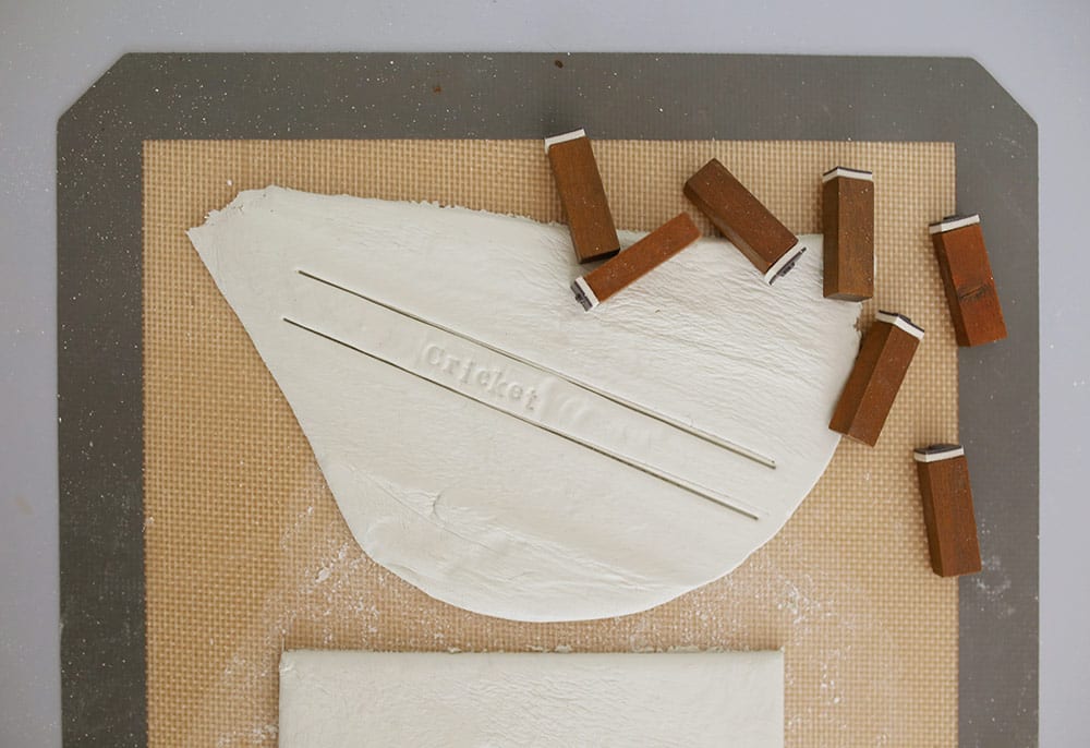 Alphabet stamps on air dry clay on a silicone baking mat to make a diy baby clay handprint keepsake frame