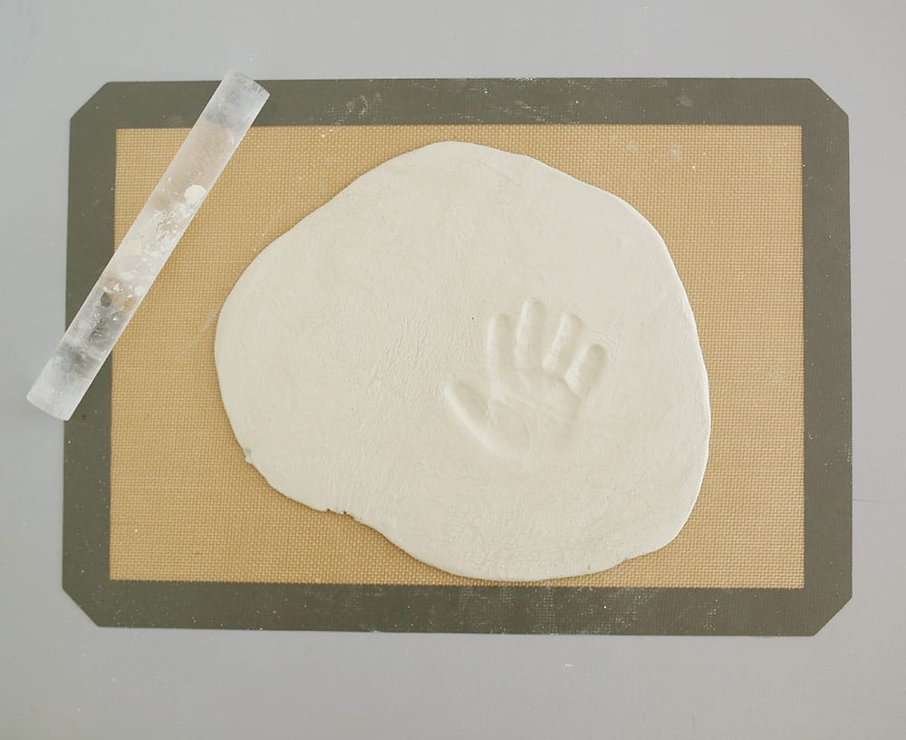 Air dry clay with infant hand print on a silicone baking mat to make a diy baby clay handprint keepsake frame