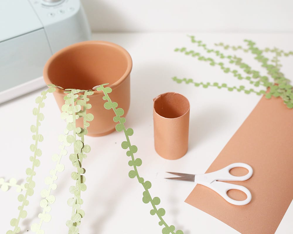 String of pearls DIY paper succulents in a terra cotta pot against a white wall