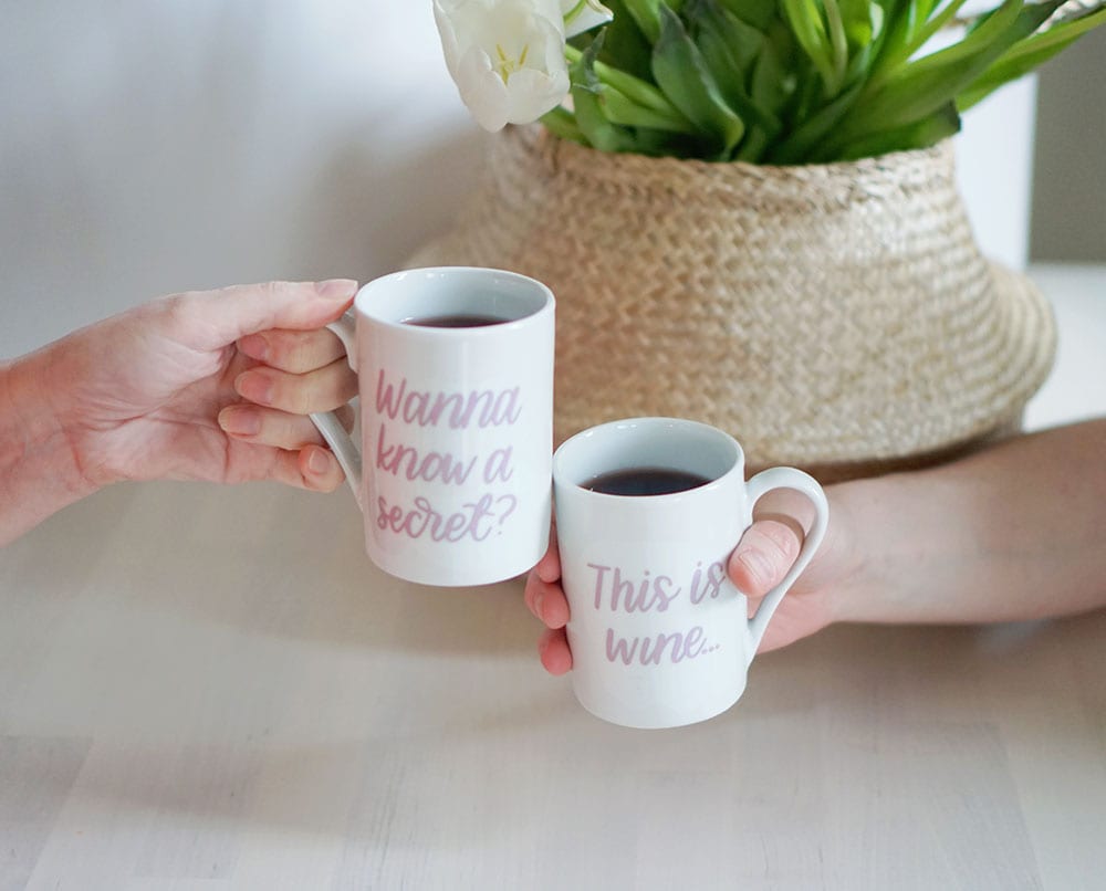 Two hands toasting with a set of this might be wine mugs
