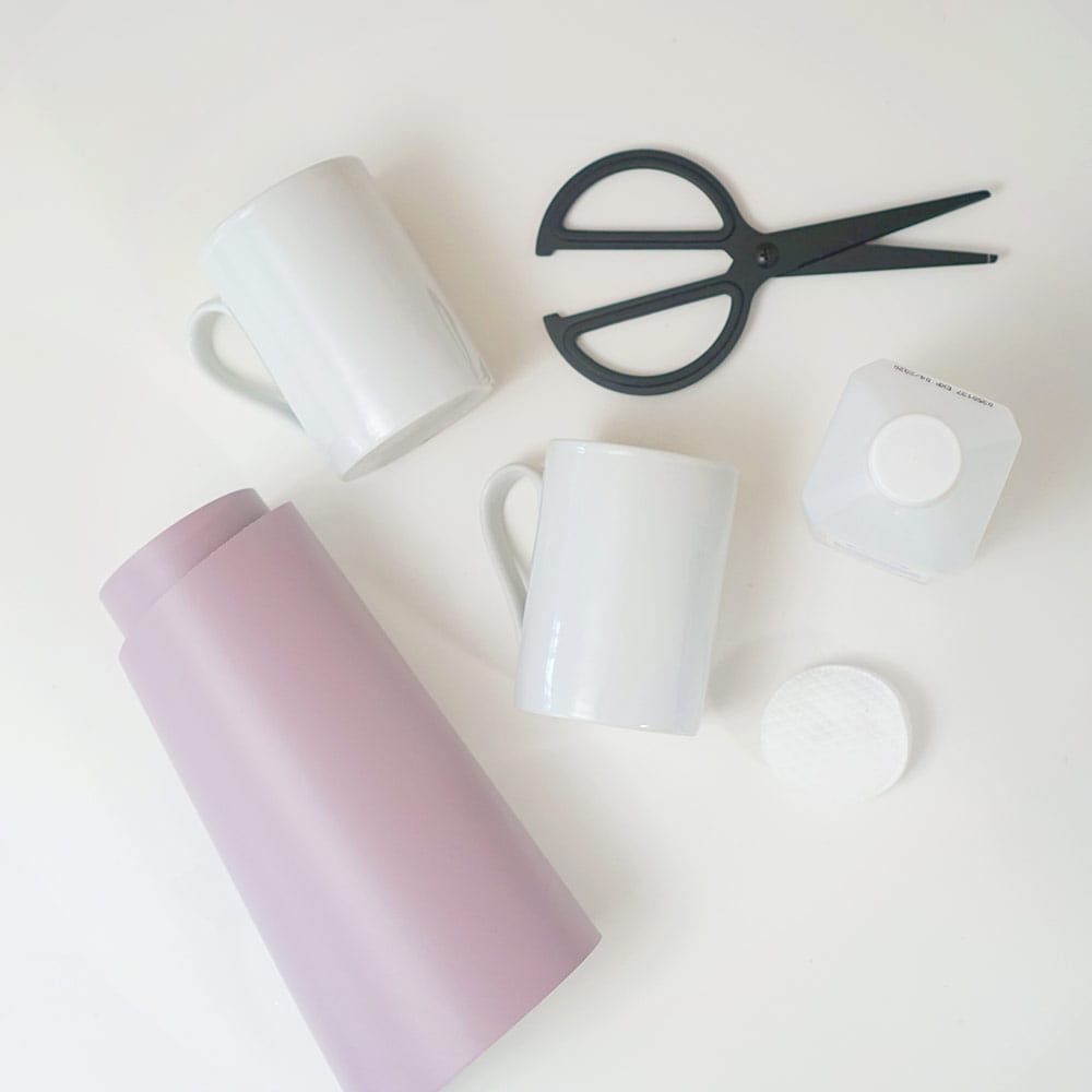 Lavender vinyl, black scissors, and white coffee cups on a white background for DIY wine mugs