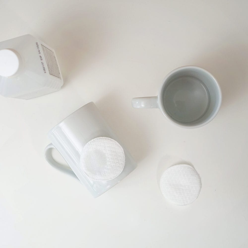White mugs and cotton pads on a white background