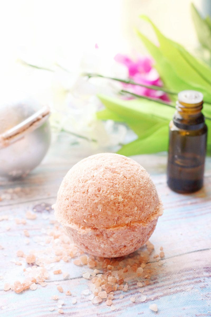 Pink Himalayan salt bath bomb recipe on a wooden background with an essential oil bottle