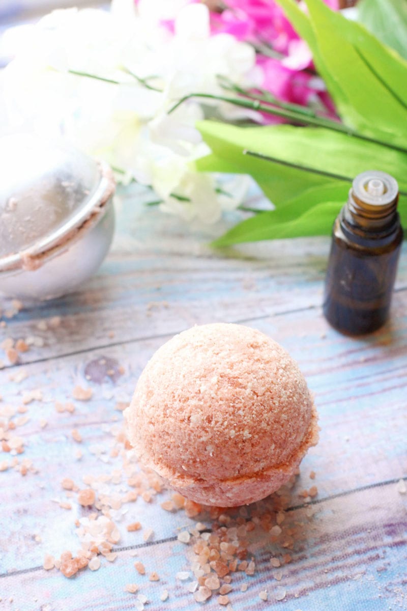 Recipe for pink Himalayan salt bath bombs on a wooden background with an essential oil bottle