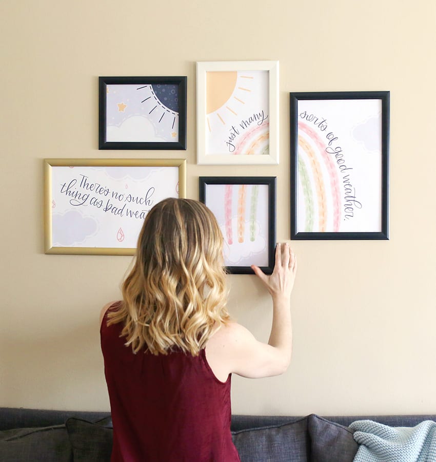 Woman with blonde ombre balayage hair puts a frame on a gallery wall