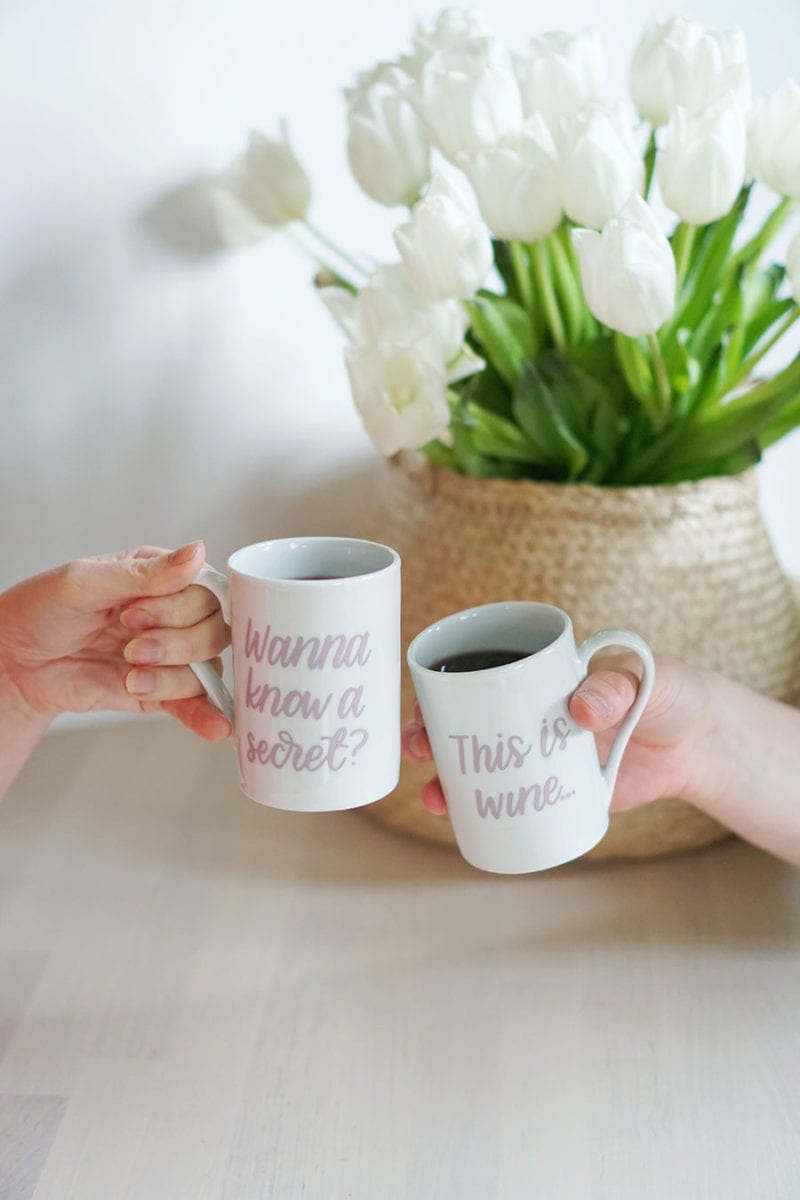 Two hands toasting with a set of this might be wine mugs