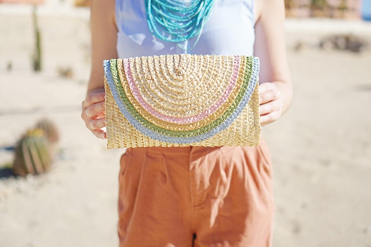 DIY a half-round straw purse for summer with this adorable rainbow clutch tutorial using regular old acrylic paint! It's ridiculously easy and can be made in a classic bright rainbow or this pretty pastel color palette for spring and summer!