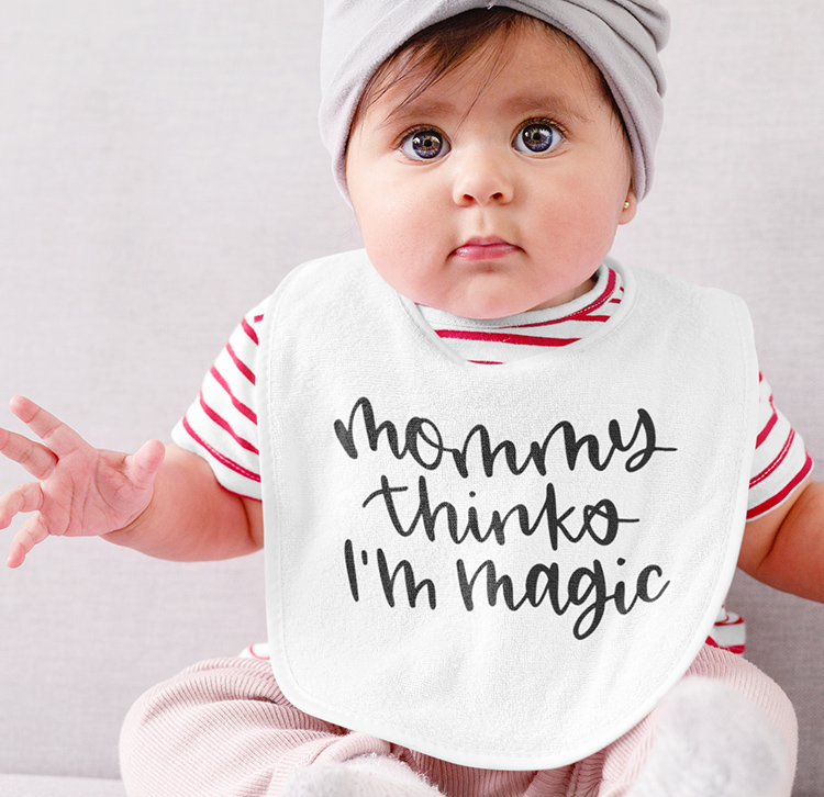 White baby with a white bib that has a free SVG cut file of Mommy Thinks I'm Magic