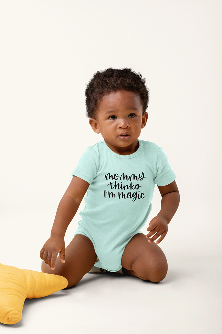 Black baby in a light blue onesie that says "Mommy Thinks I'm Magic"