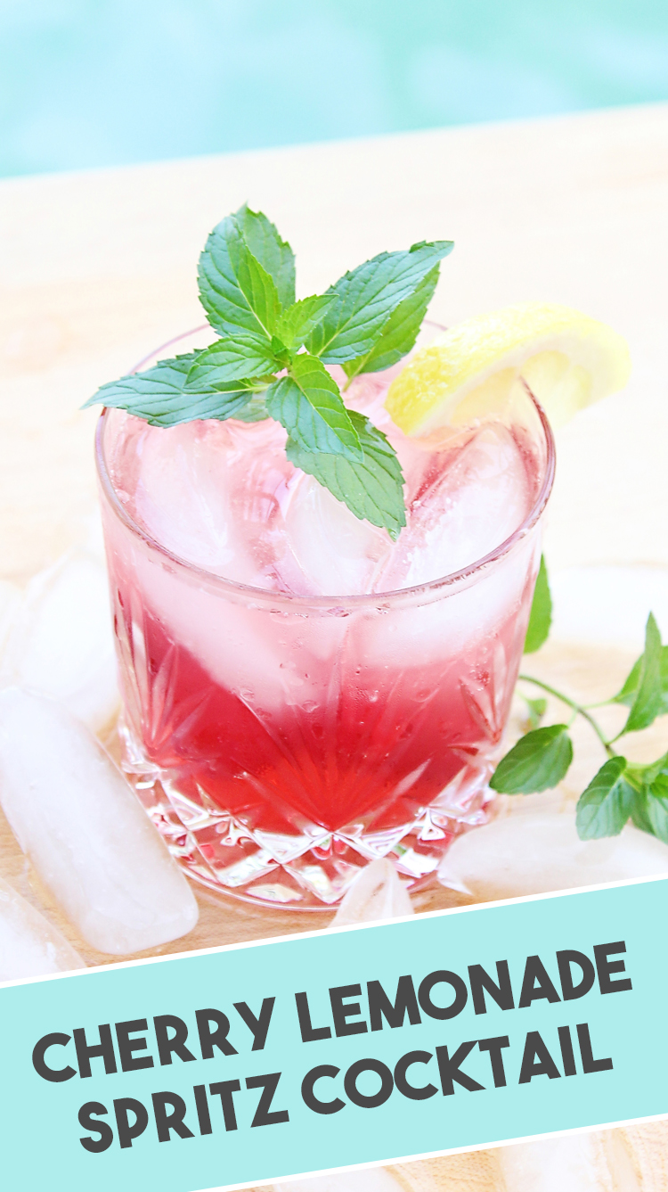 Cocktail in a rocks glass with cherry lemonade drink and a sprig of mint next to a pool for summer